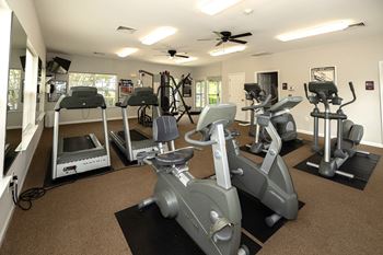 A gym with a variety of exercise equipment including treadmills, stationary bikes, and weight machines.